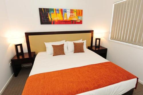 a bedroom with a large bed with an orange blanket at Gladstone Heights Executive Apartments in Gladstone