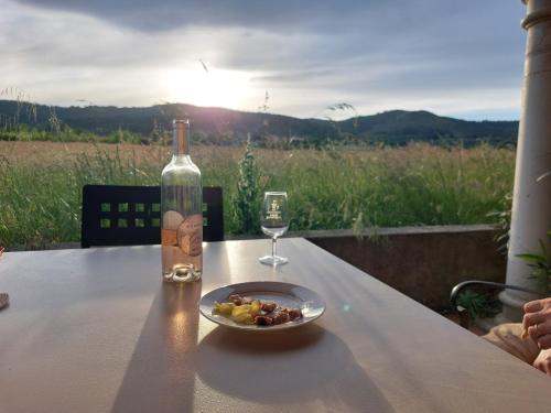 eine Flasche Wein und ein Teller mit Essen auf einem Tisch mit einem Glas in der Unterkunft La Musardière in Alba La Romaine