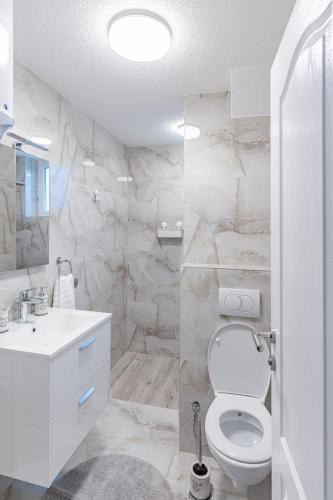 a white bathroom with a toilet and a sink at Mona Visoko in Visoko