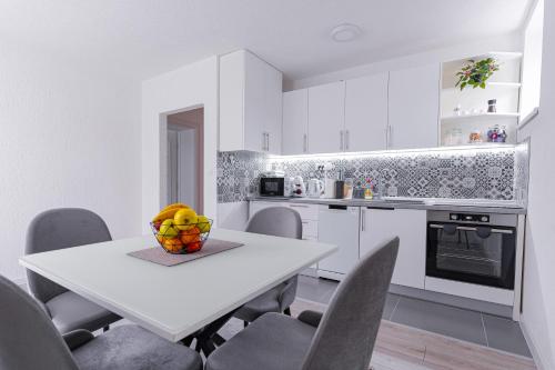 a white kitchen with a table with a bowl of fruit on it at Mona Visoko in Visoko