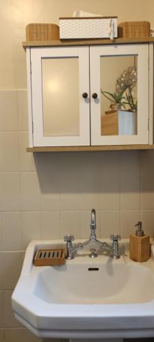 a white bathroom sink with a cabinet above it at Le Clos Baroussais in Thèbe