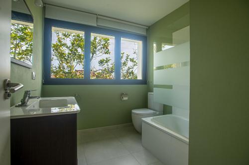 uma casa de banho com um lavatório, um WC e 2 janelas. em Casa maria em Celorio