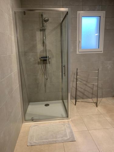 une douche avec une porte vitrée dans une salle de bain dans l'établissement Les gîtes Pléhédelais BIS, à Pléhédel