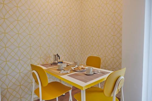 a dining table with yellow chairs and a yellow wall at Casa Gordigiani - bilocali con parcheggio in Florence