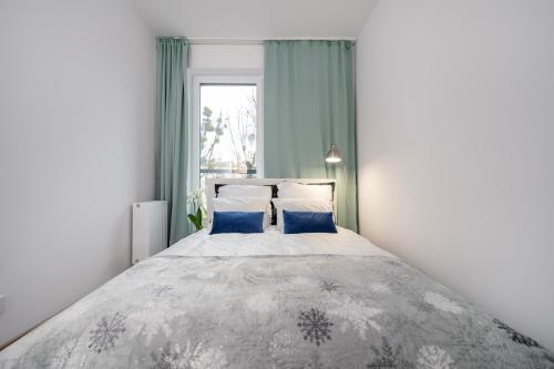 a bedroom with a large bed with blue pillows at Manufaktura Residence - Apartamenty Prestiż z Garażem Podziemnym i Dwoma Łazienkami in Łódź