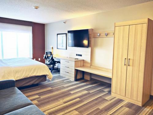 a bedroom with a bed and a desk with a television at Holiday Inn Express & Suites La Porte by IHG in LaPorte