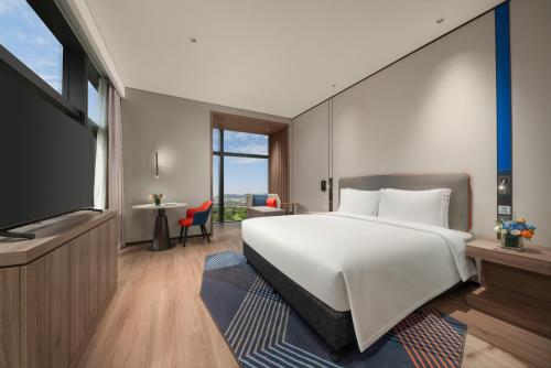 a bedroom with a large white bed and a television at Holiday Inn Express Shenzhen Futian Center by IHG in Shenzhen