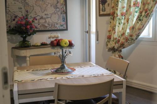 a dining room table with a bowl of fruit on a plate at Accademia Apartment in Sassari