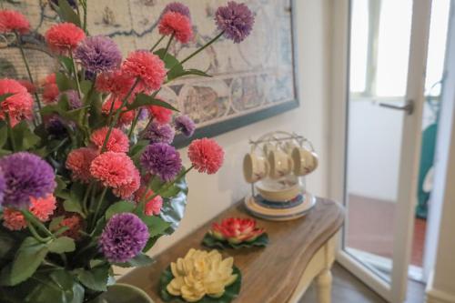 a vase of flowers on a table with a phone at Accademia Apartment in Sassari