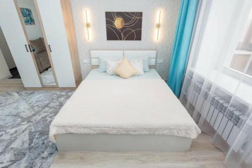een slaapkamer met een groot wit bed voor een spiegel bij Шикарная квартира в Золотом квадрате in Alma-Ata