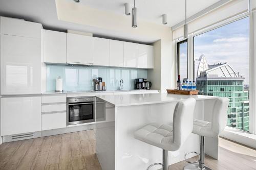 a kitchen with white cabinets and a large window at 35th FL w the BEST Views of the Stampede & Saddledome! FREE Banff Pass, Wine, Parking & Gym! in Calgary