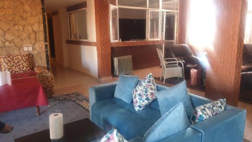 uma sala de estar com um sofá azul com almofadas em Auberge Mandar itto A station de service ZIZ em Aït nʼTaleb Akka
