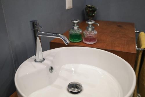 a white sink with a faucet and two bottles on a counter at Accademia Apartment in Sassari