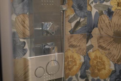 a shower with a glass door with flowers on the wall at Accademia Apartment in Sassari