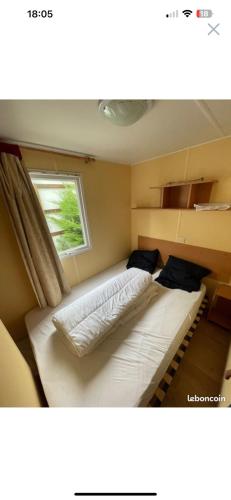 2 łóżka w małym pokoju z oknem w obiekcie mobil home numéro 76 w mieście Meschers-sur-Gironde