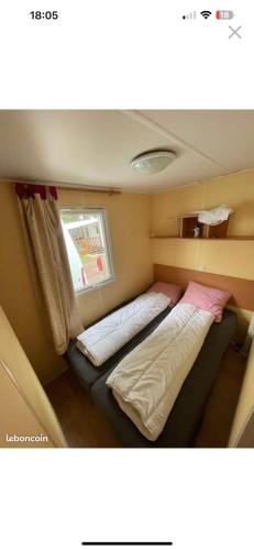 niewielka sypialnia z 2 łóżkami i oknem w obiekcie mobil home numéro 76 w mieście Meschers-sur-Gironde