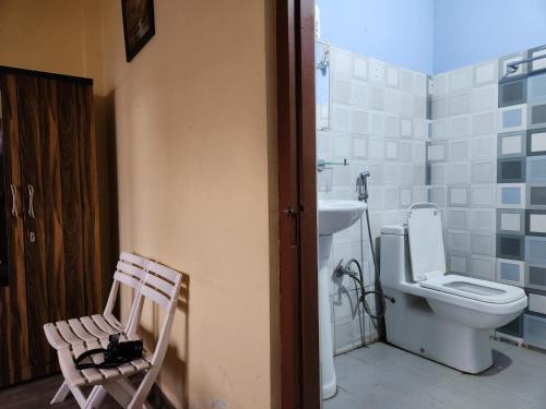 a bathroom with a toilet and a sink and a chair at Cafe Sola bnb in Shillong