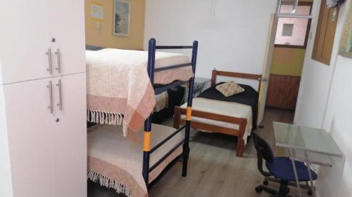 a room with three bunk beds and a refrigerator at Hostal Pampaloja Antof in Antofagasta