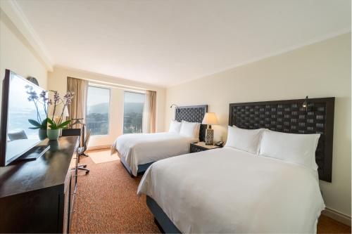 a hotel room with two beds and a desk at Hotel Real InterContinental San Pedro Sula, an IHG Hotel in San Pedro Sula