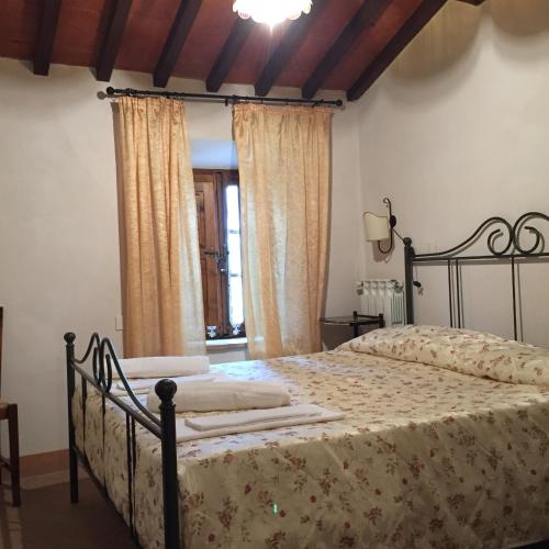 a bedroom with a bed in a room with curtains at Villa Fonte all'Oppio con area piscina recintata in Pienza