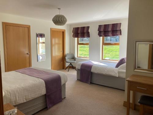 1 dormitorio con 2 camas, silla y ventanas en Lakeside House en Ballynahinch