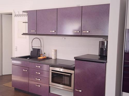 - une cuisine avec des placards violets et une cuisinière dans l'établissement Ferienwohnung an der Brauerei, à Sebnitz