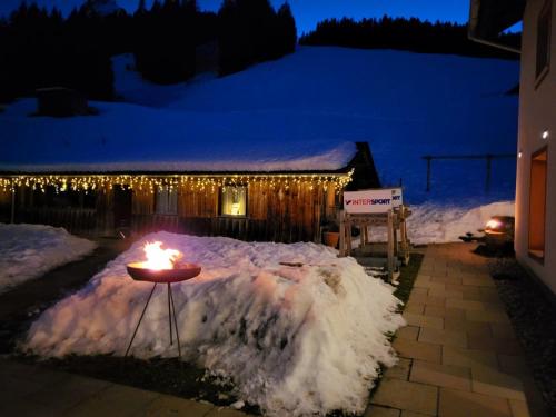 un tavolo con una candela nella neve di fronte a una casa di Berggasthof Grabs a Schruns