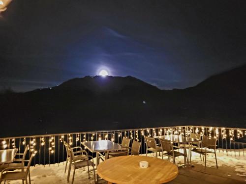 un patio con mesas y sillas por la noche con la luna en Berggasthof Grabs en Schruns