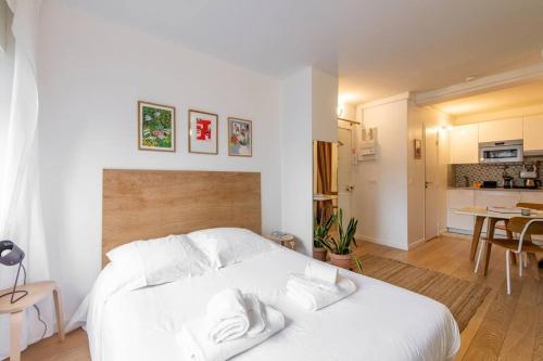 Cet appartement comprend une chambre avec un lit blanc et une cuisine. dans l'établissement Couronnes - Cosy studio tout équipé et privatif, à Paris
