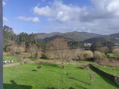 pole zielonej trawy z górami w tle w obiekcie Casa familiar con finca privada (Orolterra) w mieście Viveiro