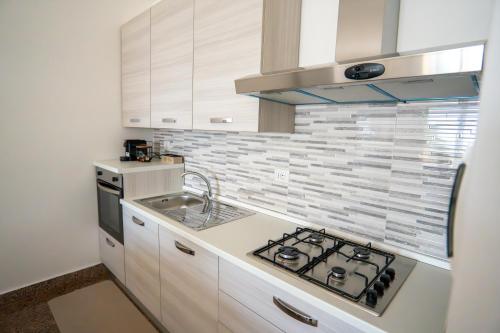 a white kitchen with a stove and a sink at Casa Erika in Bova Marina