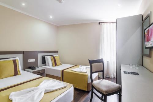 ein Hotelzimmer mit zwei Betten und einem Stuhl in der Unterkunft Ayhan Hotel in Antalya