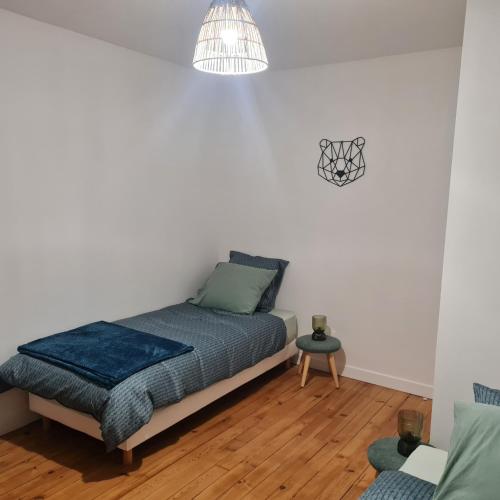 - une chambre avec un lit et une lampe pendant dans l'établissement Au rayon du soleil, à Roye