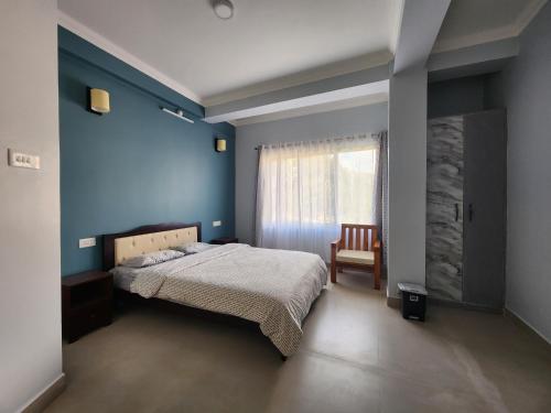 a blue bedroom with a bed and a chair at Cafe Sola bnb in Shillong