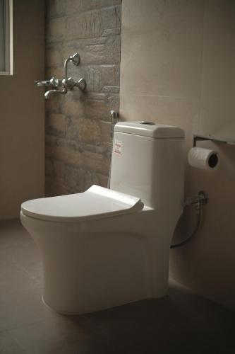 a white toilet in a bathroom with a roll of toilet paper at Cafe Sola bnb in Shillong