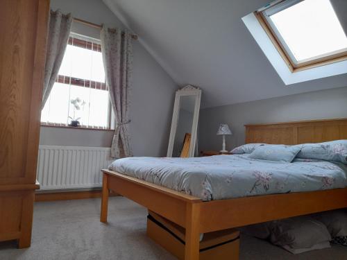a bedroom with a bed and two windows at Quarry Loft in Magherafelt