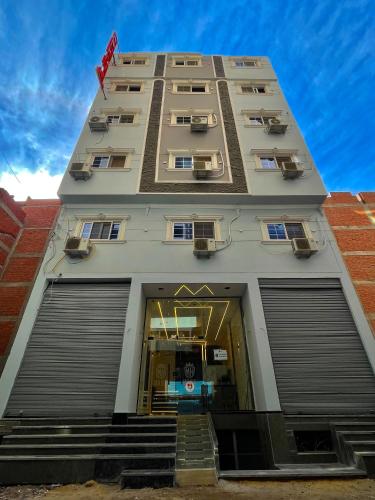 a tall white building with stairs leading up to it at MASA HOTEL APARTMENT in Mansoura