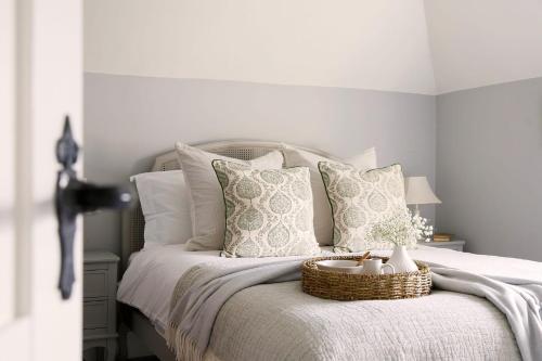 Una cama con almohadas blancas y una cesta. en Luxury Boltholes Fallow Grange, en Chichester
