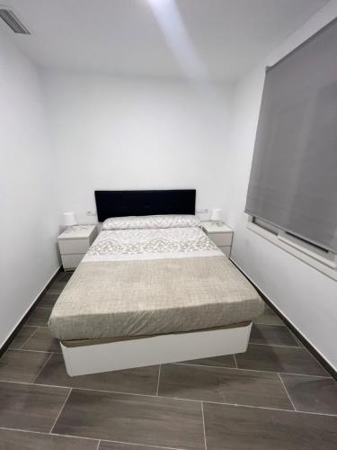 a white bedroom with a bed and two windows at Apartamentos BEACHYDAYS Metropolis B in Torremolinos