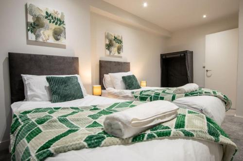 a bedroom with two beds with green and white comforters at Luxury City Centre Apartment (Weekly Booking) in Hull