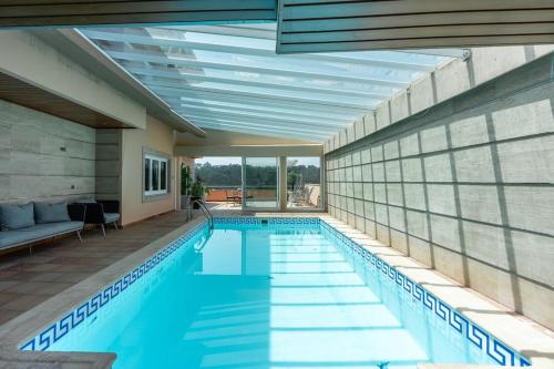 a swimming pool in a building with a glass wall at Villa Jobim in Juvim
