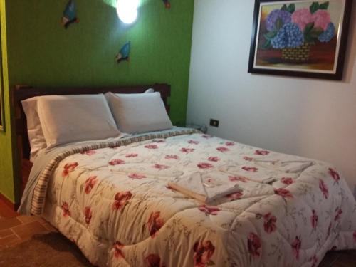 a bedroom with a large bed with a flowery bedspread at Pousada Pinhalense in Santo Antônio do Pinhal
