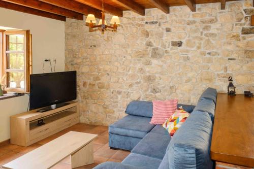 a living room with a blue couch and a stone wall at La Bolera Paraíso Astur in Llanes