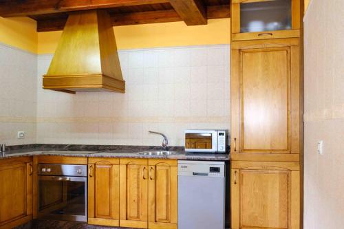 a kitchen with wooden cabinets and a sink and a microwave at La Bolera Paraíso Astur in Llanes