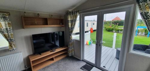 a living room with a tv and a sliding glass door at R&L'S RETREATS in Cayton