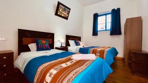 2 camas en una habitación de color azul y blanco en Hostal Tunupa, en Cusco