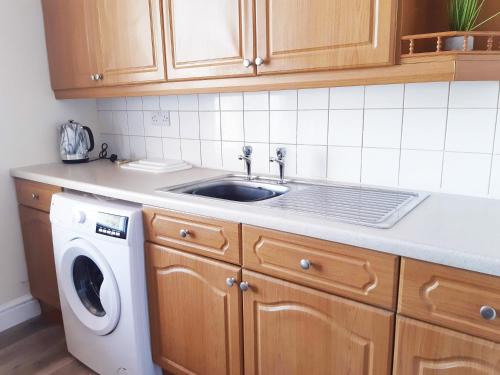 uma cozinha com um lavatório e uma máquina de lavar roupa em Pulteney Road Apartment em Bath