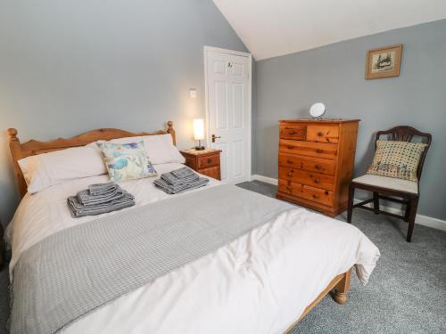 a bedroom with a bed with a dresser and a chair at 26 Tansey in Shepton Mallet