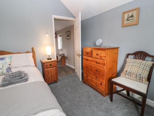 a bedroom with a bed and a dresser and a chair at 26 Tansey in Shepton Mallet