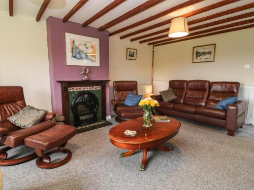 a living room with leather furniture and a fireplace at 26 Tansey in Shepton Mallet